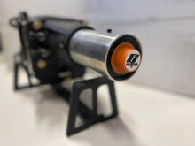 Load image into Gallery viewer, Perspective picture of a transmission on a transmission stand featuring an orange tailhousing plug installed
